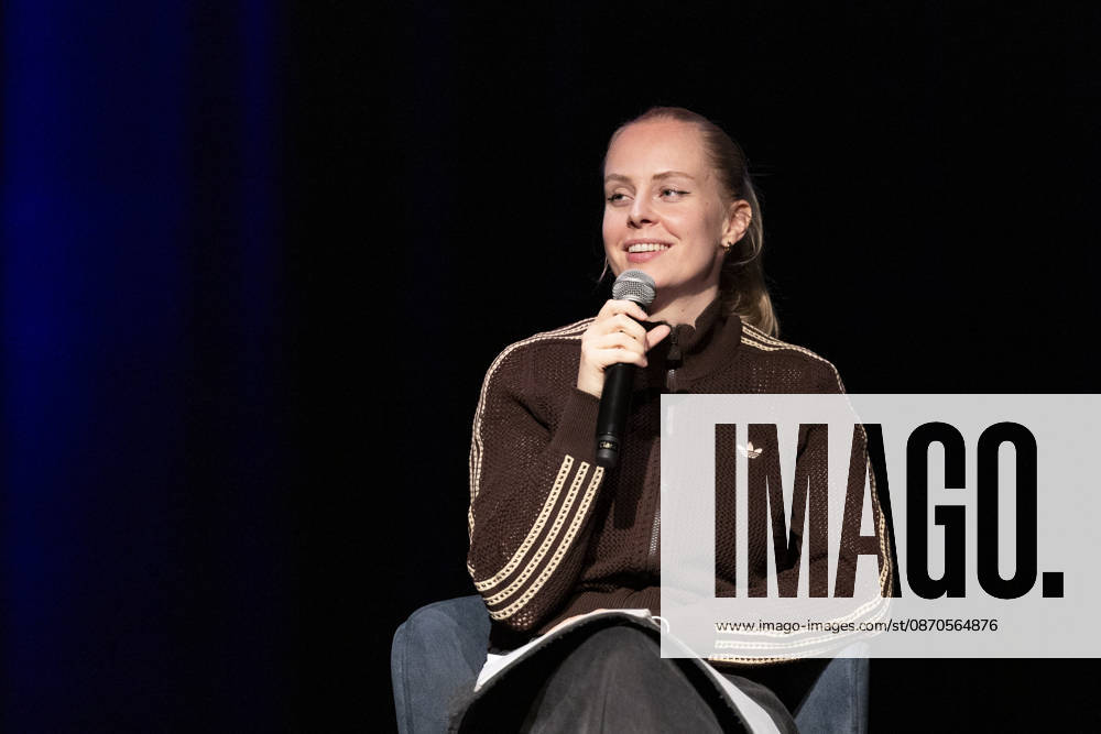 Poetry Artist, Autorin Clara LOESEL (LÖSEL) lachend, Lachen, bei ihrer Lesung, Previewshow zu ihrem neuen Buch ,Ich dachte, sowas fuehl nur ich, sitzend, mit Mikrofon, Einzelbild, Einzelfoto, im Theater am Tanzbrunnen, Koeln, am 23.10.2026.