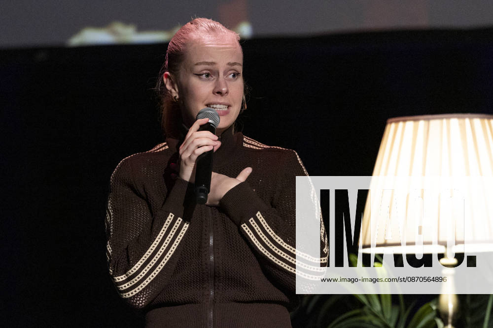 Poetry Artist, Autorin Clara LOESEL (LÖSEL) konzentriert, spricht, bei ihrer Lesung, Previewshow zu ihrem neuen Buch ,Ich dachte, sowas fuehl nur ich, stehend, mit Mikrofon, Einzelbild, Einzelfoto, im Theater am Tanzbrunnen, Koeln, am 23.10.2026.