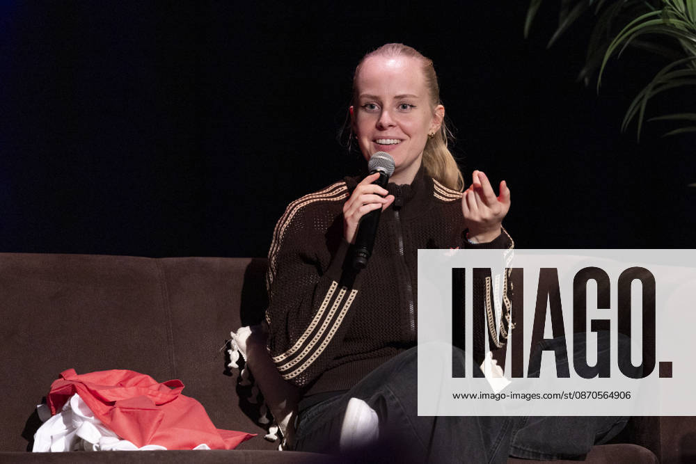 Poetry Artist, Autorin Clara LOESEL (LÖSEL) sprechend, Geste mit einer Hand, bei ihrer Lesung, Previewshow zu ihrem neuen Buch ,Ich dachte, sowas fuehl nur ich, auf einem Sofa sitzend, mit Mikrofon, Einzelbild, Einzelfoto, im Theater am Tanzbrunnen, Koeln, am 23.10.2026.