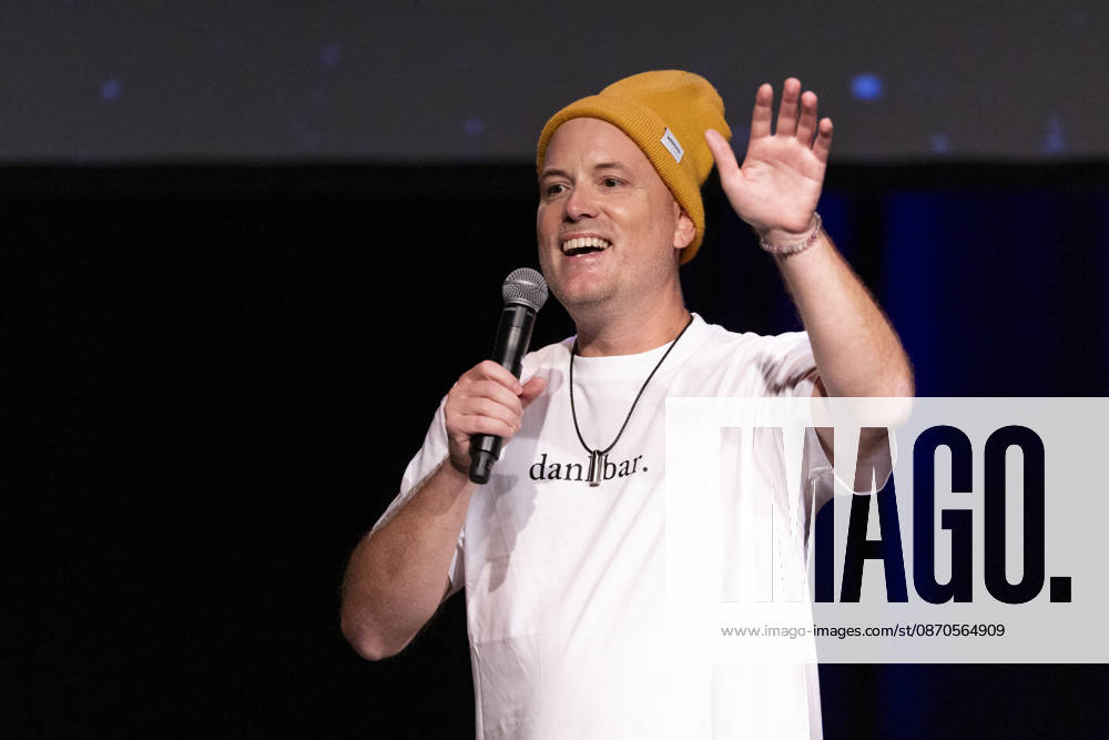 Autor, Podcaster Lars AMEND sprechend, Geste mit einer Hand, bei der Lesung von Clara Loesel (nicht im Bild), Previewshow zu ihrem neuen Buch ,Ich dachte, sowas fuehl nur ich, stehend, mit Mikrofon, Einzelbild, Einzelfoto, im Theater am Tanzbrunnen, Koeln, am 23.10.2026.