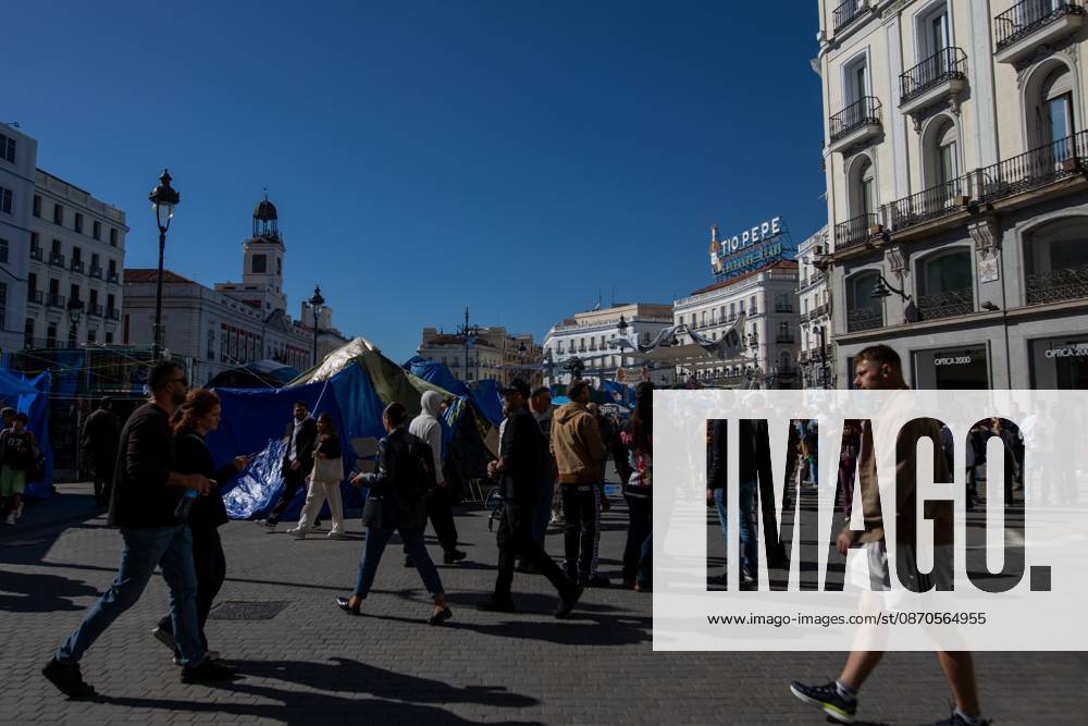 People walk in front of the tents of an encampment for decent housing, set up at Puerta del Sol..Tents remain set up by housing rights activists, who organized the occupation of the square in response to the eviction of Maricarmen a woman in her eighties from her home, carried out by a real estate investment fund. Madrid Spain - ZUMAs197 20261023_aaa_s197_154