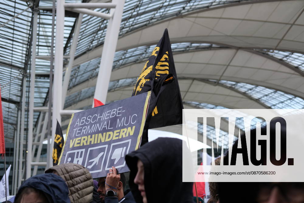 Protest at Munich Airport against planned deportation terminal MUNICH, GERMANY - OCTOBER 24: A protester holds a sign reading Abschiebeterminal MUC verhindern (Stop the MUC Deportation Terminal) as demonstrators with black flags gather inside the MAC Forum at Munich Airport in Munich, Germany on October 24, 2026. The campaign opposes plans to build a deportation terminal at Munich Airport operational from 2028. Merve Goettl Anadolu Munich Germany. Editorial use only. Please get in touch for any other usage.