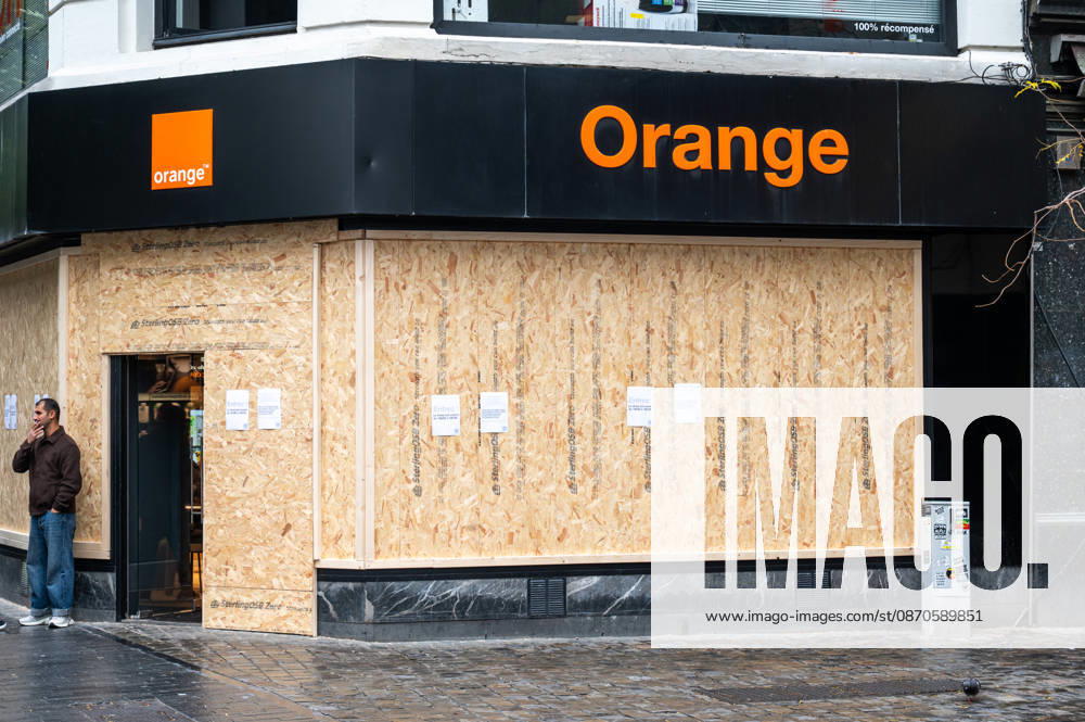 Shops around Place de la Monnaie and Rue Neuve in central Brussels, Belgium, are boarded up on 24 October 2026 amid student protests. Large groups of people move through the commercial district in rainy, unsettled weather, creating a sombre urban atmosphere as businesses protect their premises with wooden panels.