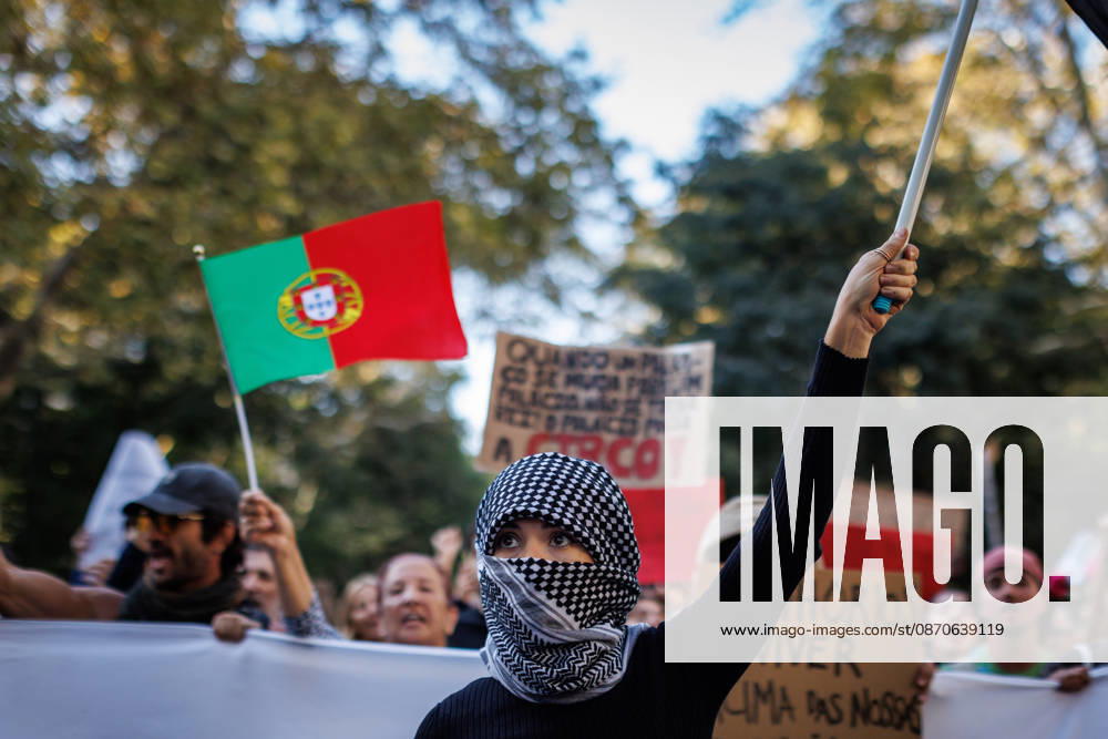 A protester with her face covered raises a flag at the front line during the demonstration. People march through central Lisbon during a demonstration demanding affordable housing and protesting against the rising cost of living. The protest started at Marques de Pombal and ended at Rossio Square, where demonstrators set up tents at the end of the march in protest against Portugal s housing crisis. Lisbon Portugal - ZUMAs197 20261024_aaa_s197_589