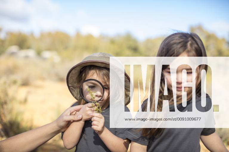 Girls examining plant with magnifying glass model released Symbolfoto property released ZEF16073