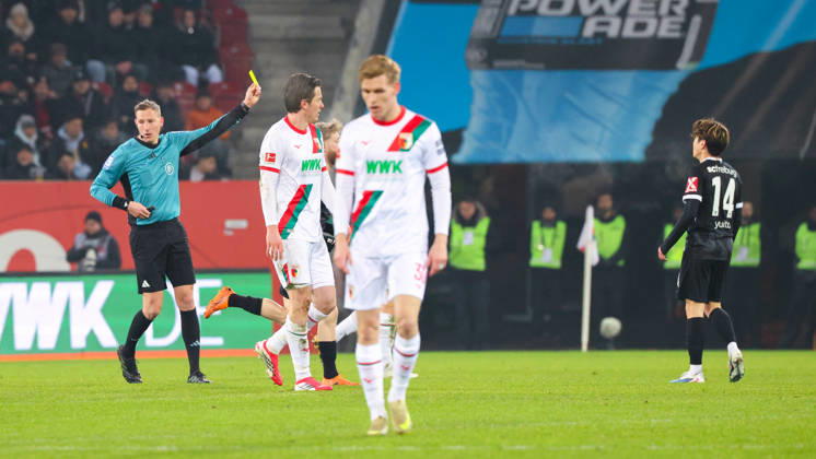 Martin Petersen (Schiedsrichter) zeigt Yuito Suzuki (14, SC Freiburg), die gelbe Karte beim Spiel zwischen FC Augsburg v SC Freiburg, Fußball, Herren, Bundesliga, 2025 2026, 18.Spieltag am 18.01.2026 in Augsburg, WWK-Arena. DFL and DFB regulations prohibit any use of photographs as image sequences and or quasi-video. Bayern Deutschland