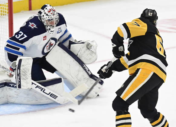 Pittsburgh Penguins right wing Rickard Rakell (67) scores on Winnipeg Jets goaltender Connor Hellebuyck (37) during the overtime penalty shot shootout in the Pittsburgh Penguins 5-4 win at PPG Paints Arena in Pittsburgh on Saturday, March 21, 2026. PIT2026032113 ARCHIExCARPENTER