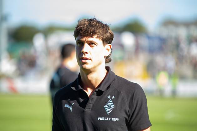 Ein Offizieller von Borussia Mönchengladbach steht im schwarzen Vereins-Polo mit Puma-Logo und REUTER-Sponsoring vor dem Spielfeld. Im Hintergrund sind Zuschauer und das Spielfeld zu erkennen. Borussia Mönchengladbach – Offizieller in Velbert Copyright: xJonasxHunoldx