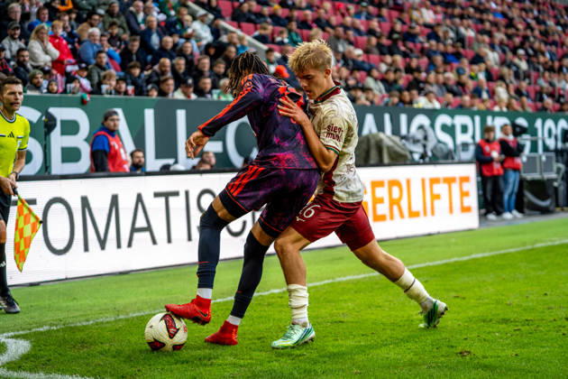 Michael Olise (17 Bayern) und Hennes Behrens (16 Augsburg) in Aktion beim Bundesligaspiel FC Augsburg - FC Bayern München am 10.10.2026.