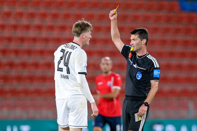 Andreas Dinger (Schiedsrichter, Referee) zeigt Benedikt Kuhn (Landsberg, 24) die Gelbe Karte, Verwarnung, yellow card, 13.10.2026, Unterhaching (Deutschland), Fussball, Regionalliga Bayern, SpVgg Unterhaching - TSV 1882 Landsberg