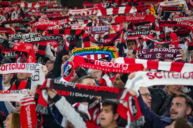 Deutschland: Fussball UEFA Conference League 2026 - 2027, 1. Spieltag - SC Freiburg vs FK Jablonec - Europa-Park-Stadion (Freiburg): Fans des SC Freiburg halten auf der Tribüne des Europa-Park-Stadions zahlreiche rot-weisse und schwarz-rote Fanschals in die Höhe. Geschlossenes Fanbild beim UEFA Conference League-Spiel gegen FK Jablonec. Sichtbar ist auch ein Regenbogenschal mit der Aufschrift Freiburg ist bunt. SC Freiburg, FK Jablonec, Fussball, Europapokal, Fans, Zuschauer, Fankultur, Fanblock, Fanschals, Vereinsfarben, Solidarität, Vielfalt, Diversität, Toleranz, LGBTQ, Stimmung, Heimfans, Supporter, Fanartikel, Stadion. Copyright: xJOERANxSTEINSIEKx