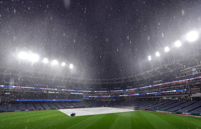A tarp covers the infield as a heavy rain falls before the start of game four of the MLB, Baseball Herren, USA American League Championship Series between the Tampa Bay Rays and the Cleveland Guardians at Progressive Field in Cleveland, Ohio, on Friday, October 16, 2026. The 8pm ET start of the game has been delayed due to the weather.  CLE20261016703 AARONxJOSEFCZYK
