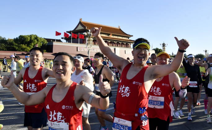 (261018) -- BEIJING, Oct. 18, 2026 -- Runners waves to cameras as they compete during the 2026 Beijing Marathon & National Marathon Championships in Beijing, capital of China, Oct. 18, 2026. ) (SP)CHINA-BEIJING-2026 BEIJING MARATHON(CN) LixXin 