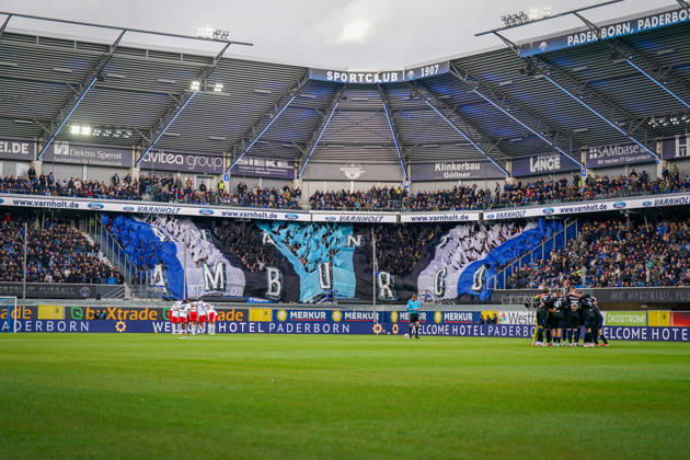 Deutschland: Fussball Bundesliga 2026 - 2027, 7. Spieltag - SC Paderborn vs Hamburger SV - Home-Deluxe-Arena (Paderborn): Totale der Home-Deluxe-Arena in Paderborn, Innenansicht mit grosser blau-schwarz-weisser Choreographie der Heimfans des SC Paderborn 07 auf der Tribüne, Schriftzug HAMBURG. Fanchoreo, Ultras, Fanszene, Zuschauer, Fahnen, Fanblock, Stimmung, Mannschaftskreise beider Teams vor Spielbeginn, Hamburger SV, HSV, SC Paderborn, Fussball, Bundesliga, Sportstätte, Stadiondach, Flutlicht, Spielfeld, Sponsoren, Werbung, Werbebanden, Merkur, buXtrade, Varnholt, Welcome Hotel. Copyright: xJOERANxSTEINSIEKx