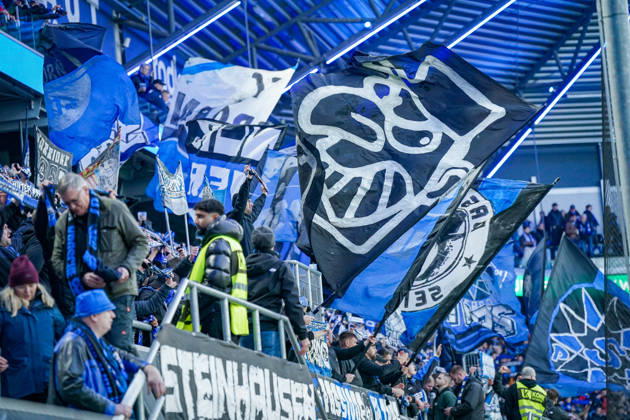 Deutschland: Fussball Bundesliga 2026 - 2027, 7. Spieltag - SC Paderborn vs Hamburger SV - Home-Deluxe-Arena (Paderborn): Heimfans des SC Paderborn 07 feiern auf der Tribüne der Home-Deluxe-Arena den Heimsieg gegen den Hamburger SV (HSV). Zahlreiche grosse blau-schwarz-weisse Fahnen mit Vereinswappen und Fanmotiven. Fans, Ultras, Fanszene, Fankultur, Fankurve, Fanblock, Zuschauer, Fahnenmeer, Jubel, Siegesfeier, Stimmung, Emotionen, Support, Fangesänge, Tribüne, Bundesliga, Fussball, Sportstätte, Innenansicht, Stadiondach, Flutlicht, Sicherheitsdienst, Ordnungsdienst. Copyright: xJOERANxSTEINSIEKx