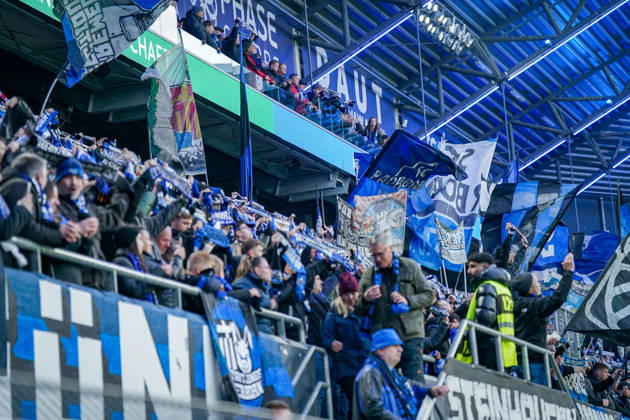 Deutschland: Fussball Bundesliga 2026 - 2027, 7. Spieltag - SC Paderborn vs Hamburger SV - Home-Deluxe-Arena (Paderborn): Heimfans des SC Paderborn 07 feiern auf der Tribüne der Home-Deluxe-Arena den Heimsieg gegen den Hamburger SV (HSV). Zahlreiche grosse blau-schwarz-weisse Fahnen mit Vereinswappen und Fanmotiven. Fans, Ultras, Fanszene, Fankultur, Fankurve, Fanblock, Zuschauer, Fahnenmeer, Jubel, Siegesfeier, Stimmung, Emotionen, Support, Fangesänge, Tribüne, Bundesliga, Fussball, Sportstätte, Innenansicht, Stadiondach, Flutlicht, Sicherheitsdienst, Ordnungsdienst. Copyright: xJOERANxSTEINSIEKx