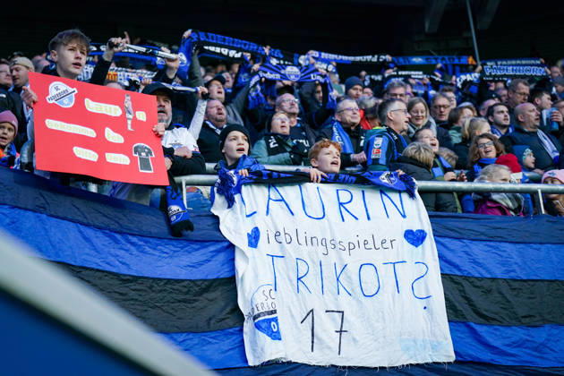 Deutschland: Fussball Bundesliga 2026 - 2027, 7. Spieltag - SC Paderborn vs Hamburger SV - Home-Deluxe-Arena (Paderborn): Junge Fans des SC Paderborn 07 auf der Tribüne der Home-Deluxe-Arena mit selbst gebastelten Transparenten LAURIN Lieblingsspieler TRIKOT? 17 und Laurin bekomme ich bitte Dein Trikot. Kinder, Nachwuchsfans, Trikotwunsch, Fanaktion, Zuschauer, Fankultur, Fussballbegeisterung, Fanschals, Fanbanner, Spruchband, Heimfans, Fankurve, Emotionen, Bundesliga, Fussball, SC Paderborn, Hamburger SV, HSV, Stadion, Sportstätte, Kinderfans, Fanliebe. Copyright: xJOERANxSTEINSIEKx