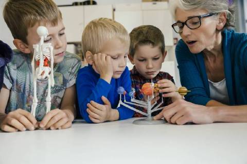 Pre-school teacher explaining solar system model to boys in kindergarten model released Symbolfoto property released  MFF04126