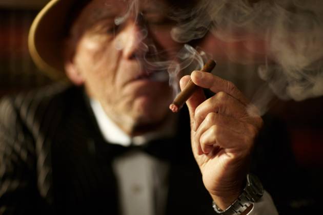 Old man, smoking and cigarette in hand with smoke and crime boss of mob with a decision. Gangster, face and senior person with vintage cigar in mafia or country club with luxury, vice or habit. model released property released Copyright: xPeopleImages.comx-x 51ac47fe55bc5x