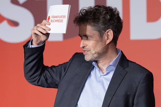 Buchmesse Frankfurt 2025 Dr. Torsten Casimir (Sprecher Frankfurter Buchmesse) begrüßt die anwesenden Pressevertreter, fühlt sich jedoch geblendet und hält sich ein Papier schützend vor die Augen. Buchmesse Frankfurt 2025., Frankfurt am Main Hessen Deutschland Messegelände