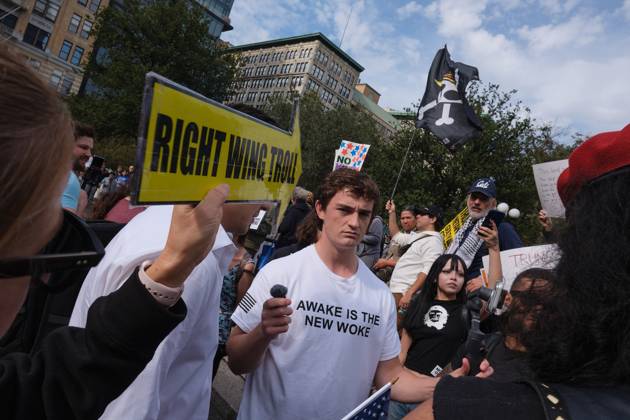 October 19, 2025, New York, New York, USA: A protester holds up a yellow arrow that reads, â€oeRight Wing Troll†pointed towards right wing social media influencer, Nick Shirley wearing a Turning Point tee shirt with the phrase, â€oeAwake Is The New Woke†who is attempting to engage people who attended the New York City No Kings protest with MAGA talking points to solicit reactions for a livestream video in Union Square. New York USA - ZUMAl171 20251019_znp_l171_002 Copyright: xEdnaxLeshowitzx