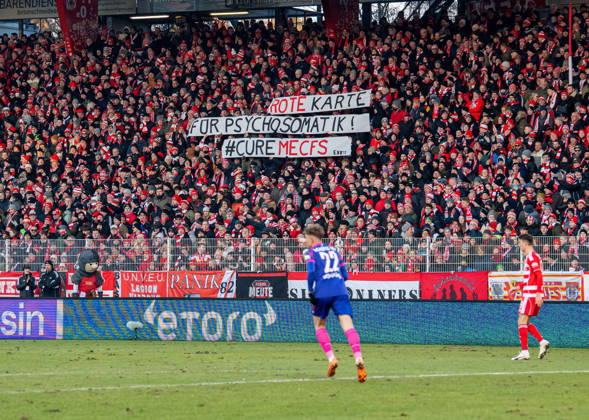 Fußball, Herren, Saison 2025 2026, 1. Bundesliga (16. Spieltag), 1. FC Union Berlin - 1. FSV Mainz 05, Fans von Union mit Transparenten: Rote Karte für Psychosomatik! CureMECFS, 10.01.2026, Copyright: xSebastianxRäppold MatthiasxKochx