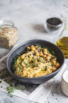 Kichererbsenhummus in der schwarzen Schale, dekoriert mit Sesamsamen und Kichererbsengrün. Vegane Rezepte, Gerichte auf pflanzlicher Basis. Konzept für umweltfreundliches Wohnen. Biologische Lebensmittel. Vegetarische Küche Chickpeas hummus in the black bowl decorated with sesame seeds and chickpeas greens. Vegan recipes, plant-based dishes. Green living concept. Organic food. Vegetarian cuisine Copyright: imageBROKER NataliiaxZhekova ibxiqx16147412