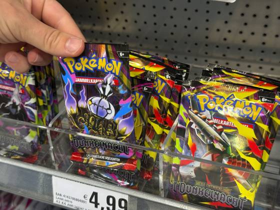 05.08.2026, Deutschland, Bayern, Pokemon-Sammelkarten im Regal eines Supermarktes in Bayern, ein junges Mädchen (Teenager) greift nach einem Päckchen. 05.08.2026, Pokemon 05.08.2026, Pokemon
