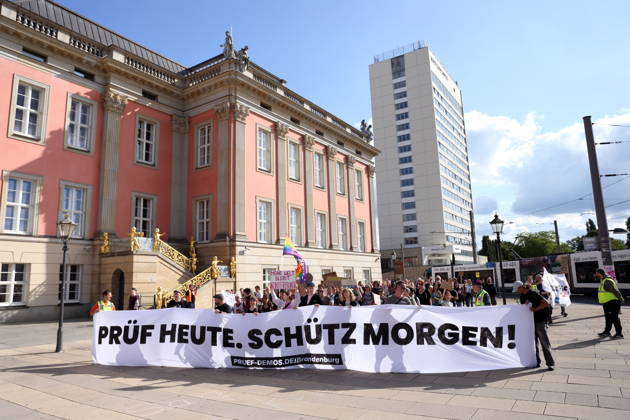 Demonstranten laufen mit Banner Prüf heute. Schütz morgen! um den Landtag während einer Demonstration für die Überprüfung rechtsextremer Parteien durch das Bundesverfassungsgericht, Alter Markt, Potsdam, 12. September 2026. Prüf-Demo in Potsdam