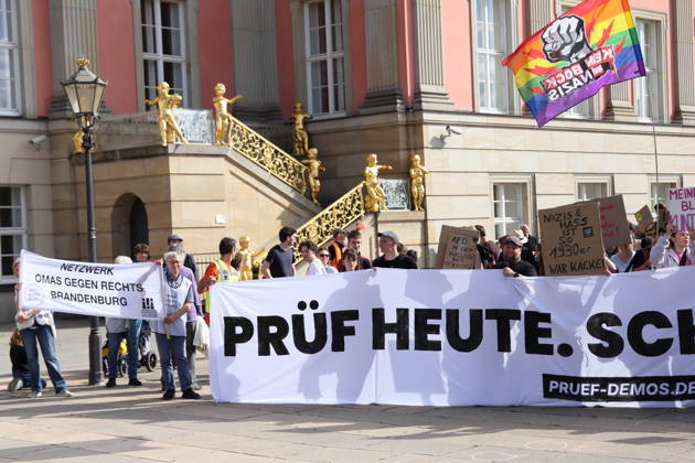 Demonstranten laufen mit Banner Prüf heute. Schütz morgen! um den Landtag während einer Demonstration für die Überprüfung rechtsextremer Parteien durch das Bundesverfassungsgericht, Alter Markt, Potsdam, 12. September 2026. Prüf-Demo in Potsdam