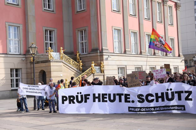 Demonstranten laufen mit Banner Prüf heute. Schütz morgen! um den Landtag während einer Demonstration für die Überprüfung rechtsextremer Parteien durch das Bundesverfassungsgericht, Alter Markt, Potsdam, 12. September 2026. Prüf-Demo in Potsdam