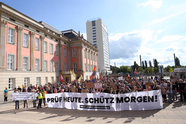 Demonstranten laufen mit Banner Prüf heute. Schütz morgen! um den Landtag während einer Demonstration für die Überprüfung rechtsextremer Parteien durch das Bundesverfassungsgericht, Alter Markt, Potsdam, 12. September 2026. Prüf-Demo in Potsdam