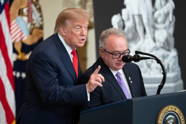 Brett Rugo, founder of Rugo Stone which constructed a helipad on the South Lawn, stands with President Donald Trump salutes during an event in the East Room of the White House in Washington, DC on Friday, Oct. 9, 2026. Trump is hosting a Columbus Day celebration. WASP20261009118 AaronxSchwartz