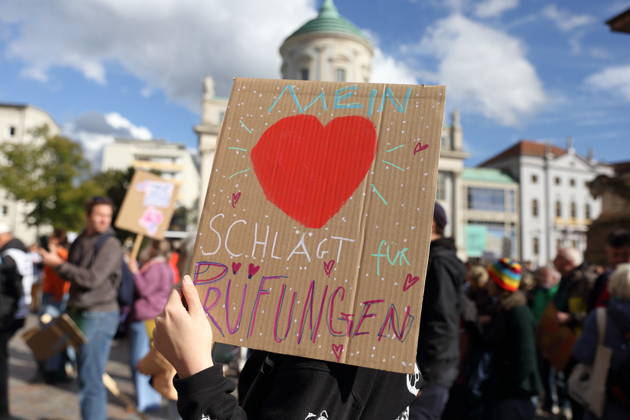 Eine Demonstrantin steht mit Schild Mein Herz schlägt für Prüfungen auf dem Alten Markt während einer Demonstration für die Überprüfung rechtsextremer Parteien durch das Bundesverfassungsgericht, Potsdam, 10. Oktober 2026. Prüf-Demo in Potsdam