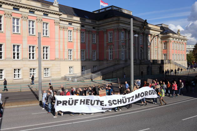 Demonstranten laufen mit Banner Prüf heute. Schütz morgen! am Landtag während einer Demonstration für die Überprüfung rechtsextremer Parteien durch das Bundesverfassungsgericht, Potsdam, 10. Oktober 2026. Prüf-Demo in Potsdam