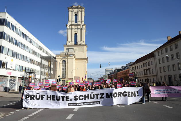 Demonstranten stehen mit Banner Prüf heute. Schütz morgen! auf der Breiten Straße während einer Demonstration für die Überprüfung rechtsextremer Parteien durch das Bundesverfassungsgericht, Potsdam, 10. Oktober 2026. Prüf-Demo in Potsdam