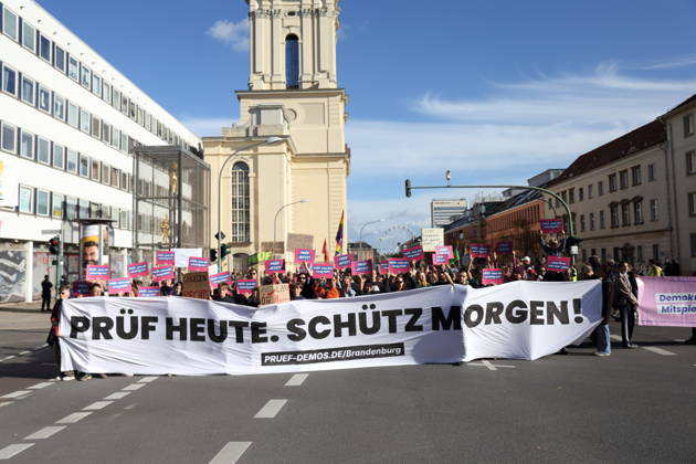 Demonstranten stehen mit Banner Prüf heute. Schütz morgen! auf der Breiten Straße während einer Demonstration für die Überprüfung rechtsextremer Parteien durch das Bundesverfassungsgericht, Potsdam, 10. Oktober 2026. Prüf-Demo in Potsdam