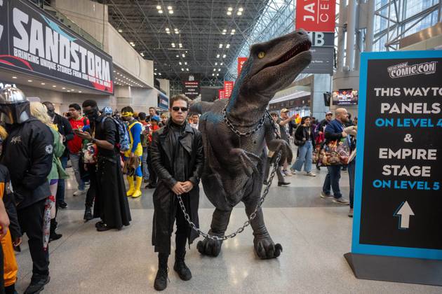 October 11, 2026, New York, New York, United States: A cosplayer dressed in a long black leather coat and dark sunglasses posing alongside a person in a realistic animatronic Velociraptor costume (resembling Blue from Jurassic World).during New York Comic Con 2026 at The Jacob K. Javits Convention Center on October 11, 2026 in New York City. New York United States - ZUMAs197 20261011_aaa_s197_352 Copyright: xRonxAdarx