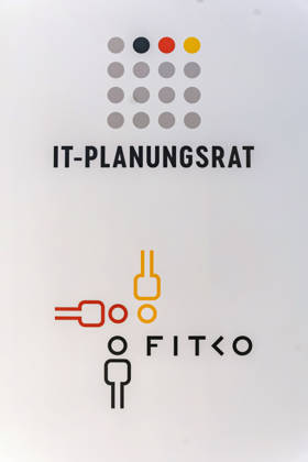 Berlin, 13.10.2026: Die Logos des IT-Planungsrats und der FITKO (Föderale IT-Kooperation) prangen auf einer Wand bei der Smart Country Convention in der Halle hub27. Der IT-Planungsrat ist das zentrale politische Gremium von Bund und Ländern für die Zusammenarbeit in der Informationstechnik und treibt unter anderem die Umsetzung des Onlinezugangsgesetzes voran; die FITKO mit Sitz in Frankfurt am Main unterstützt ihn als operative Einheit bei der Digitalisierung der Verwaltung. Die Smart Country Convention (SCCON) ist die Kongressmesse für die Digitalisierung des öffentlichen Sektors und wird vom Digitalverband Bitkom gemeinsam mit der Messe Berlin veranstaltet. Vom 13. bis 15. Oktober 2026 treffen sich in der Halle hub27 Vertreter aus