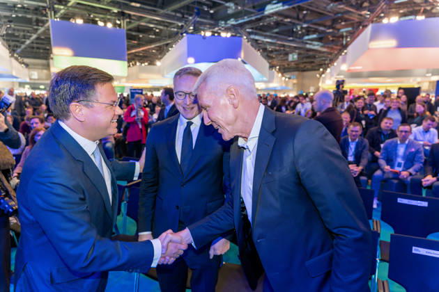 Berlin, 13.10.2026: Der portugiesische Minister Goncalo Saraiva Matias (links) und Bitkom-Präsident Ralf Wintergerst (rechts) begrüßen sich im Kongressbereich der Smart Country Convention in der Halle hub27 per Handschlag, in der Mitte lächelt Bundesdigitalminister Karsten Wildberger. Portugal ist Partnerland der Smart Country Convention 2026 und präsentiert dort seine Erfahrungen mit der Digitalisierung der öffentlichen Verwaltung. Ralf Wintergerst ist seit 2023 Präsident des Digitalverbands Bitkom. Karsten Wildberger ist seit Mai 2025 Bundesminister für Digitales und Staatsmodernisierung und leitet das damals neu geschaffene Ministerium, das die Digitalisierung von Staat und Verwaltung bündeln soll; zuvor war der Manager Vorstan