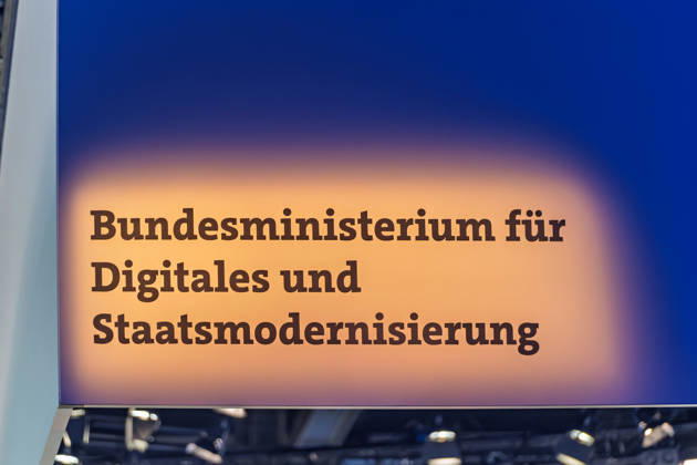 Berlin, 13.10.2026: Der beleuchtete Schriftzug Bundesministerium für Digitales und Staatsmodernisierung am Messestand des Ministeriums auf der Smart Country Convention. Das 2025 gegründete Ministerium unter Karsten Wildberger soll die Digitalisierung des Staates bündeln. Die Smart Country Convention (SCCON) ist die Kongressmesse für die Digitalisierung des öffentlichen Sektors und wird vom Digitalverband Bitkom gemeinsam mit der Messe Berlin veranstaltet. Vom 13. bis 15. Oktober 2026 treffen sich in der Halle hub27 Vertreter aus Bund, Ländern und Kommunen mit Unternehmen der Digitalwirtschaft, um über digitale Verwaltung, Smart City und digitale Souveränität zu diskutieren. Schriftzug des Bundesdigitalministeriums