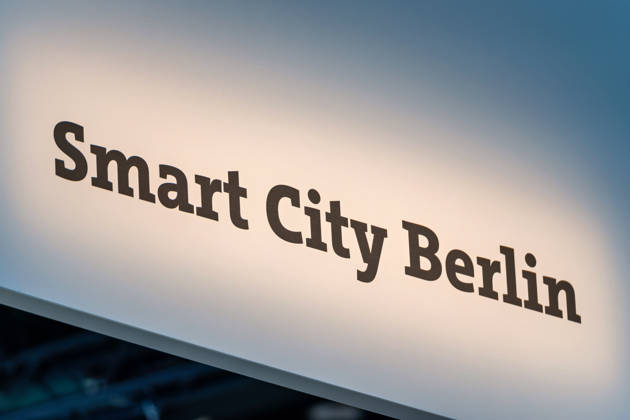 Berlin, 13.10.2026: Der beleuchtete Schriftzug Smart City Berlin an einem Deckenaufbau über dem Messestand des Landes Berlin auf der Smart Country Convention. Unter dem Begriff Smart City bündelt die Hauptstadt Projekte, mit denen digitale Technologien Verwaltung, Mobilität und Stadtentwicklung verbessern sollen. Die Smart Country Convention (SCCON) ist die Kongressmesse für die Digitalisierung des öffentlichen Sektors und wird vom Digitalverband Bitkom gemeinsam mit der Messe Berlin veranstaltet. Vom 13. bis 15. Oktober 2026 treffen sich auf dem Berliner Messegelände Vertreter aus Bund, Ländern und Kommunen mit Unternehmen der Digitalwirtschaft, um über digitale Verwaltung, Smart City und digitale Souveränität zu diskutiere