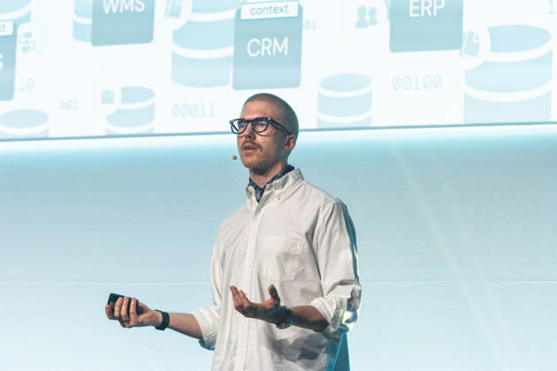 Berlin, 16.10.2026: Speaker Felix Mutzl spricht auf der Bühne der NeulandPro Connect 2026 vor einer Folie mit Unternehmenssoftware wie CRM- und ERP-Systemen. Die zweitägige KI-Konferenz NeulandPro Connect 2026 findet am 16. und 17. Oktober im Westhafen Event & Convention Center (WECC) in Moabit statt, einem historischen Speichergebäude am Berliner Westhafen. Veranstalter ist NeulandPro, eine Bildungs- und Medienmarke rund um Künstliche Intelligenz. Mit Vorträgen, Workshops und Hackathons richtet sich die Konferenz vor allem an kleine und mittelständische Unternehmen, Gründer und Führungskräfte, die KI praktisch einsetzen wollen; erwartet werden bis zu 1.000 Gäste. NeulandPro Connect 2026 - KI-Konferenz in Berlin