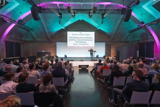 Berlin, 16.10.2026: Blick über die Zuhörer auf die Bühne der NeulandPro Connect 2026 während des Vortrags des Publizisten und Digital-Vordenkers Sascha Lobo; auf der Leinwand die Folie Die große, strategische Aufgabe: Entwicklung einer einfachen, positiven, unternehmerischen KI-Erzählung. Intern. Und Extern. Die zweitägige KI-Konferenz NeulandPro Connect 2026 findet am 16. und 17. Oktober im Westhafen Event & Convention Center (WECC) in Moabit statt, einem historischen Speichergebäude am Berliner Westhafen. Veranstalter ist NeulandPro, eine Bildungs- und Medienmarke rund um Künstliche Intelligenz. Mit Vorträgen, Workshops und Hackathons richtet sich die Konferenz vor allem an kleine und mittelständische Unternehmen, Gründer un