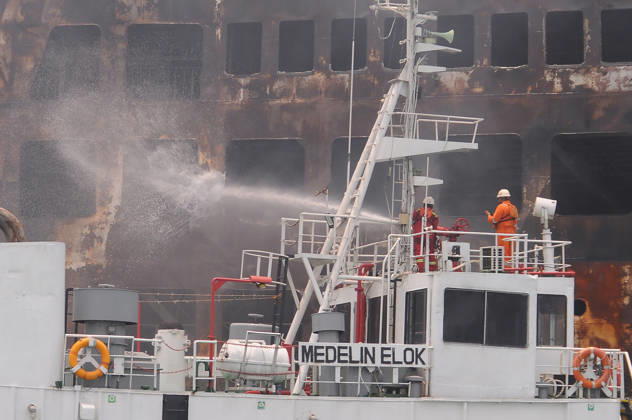 Efforts are underway to extinguish a fire that broke out on a passenger ferry in Indonesia s Cilegon PELABUHAN MERAK, CILEGON, INDONESIA - OCTOBER 21: Fireboats take turns spraying water onto the passenger ferry KMP Batumandi to cool down the vessel after it caught fire while preparing to dock off Merak Port in Cilegon, Banten, Indonesia on Wednesday, October 21, 2026. The vessel caught fire on Tuesday, October 20, and rescue operations remain underway as the ship continues to emit smoke. Water is continuously sprayed to cool the vehicle deck containing numerous cars, motorcycles, buses, and trucks, while authorities confirm no fatalities have been reported. Dasril Roszandi Anadolu Pelabuhan Merak Indonesia. Editorial use only. Please get  Copyright: x2026xAnadoluxDasrilxRoszandix