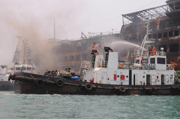 Efforts are underway to extinguish a fire that broke out on a passenger ferry in Indonesia s Cilegon PELABUHAN MERAK, CILEGON, INDONESIA - OCTOBER 21: Fireboats take turns spraying water onto the passenger ferry KMP Batumandi to cool down the vessel after it caught fire while preparing to dock off Merak Port in Cilegon, Banten, Indonesia on Wednesday, October 21, 2026. The vessel caught fire on Tuesday, October 20, and rescue operations remain underway as the ship continues to emit smoke. Water is continuously sprayed to cool the vehicle deck containing numerous cars, motorcycles, buses, and trucks, while authorities confirm no fatalities have been reported. Dasril Roszandi Anadolu Pelabuhan Merak Indonesia. Editorial use only. Please get  Copyright: x2026xAnadoluxDasrilxRoszandix