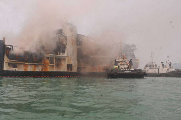 Efforts are underway to extinguish a fire that broke out on a passenger ferry in Indonesia s Cilegon PELABUHAN MERAK, CILEGON, INDONESIA - OCTOBER 21: Fireboats take turns spraying water onto the passenger ferry KMP Batumandi to cool down the vessel after it caught fire while preparing to dock off Merak Port in Cilegon, Banten, Indonesia on Wednesday, October 21, 2026. The vessel caught fire on Tuesday, October 20, and rescue operations remain underway as the ship continues to emit smoke. Water is continuously sprayed to cool the vehicle deck containing numerous cars, motorcycles, buses, and trucks, while authorities confirm no fatalities have been reported. Dasril Roszandi Anadolu Pelabuhan Merak Indonesia. Editorial use only. Please get  Copyright: x2026xAnadoluxDasrilxRoszandix