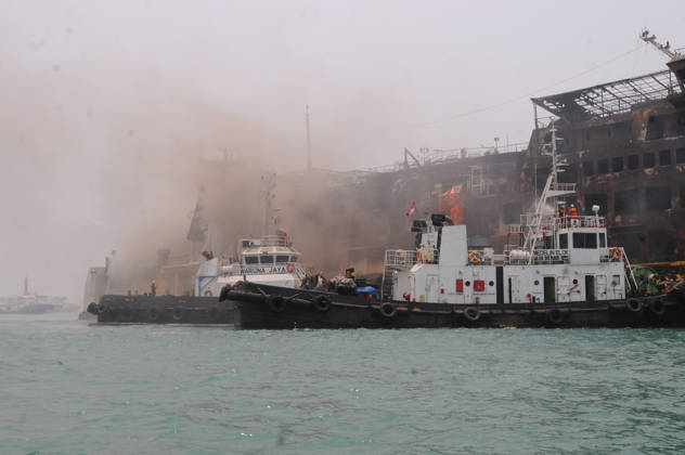 Efforts are underway to extinguish a fire that broke out on a passenger ferry in Indonesia s Cilegon PELABUHAN MERAK, CILEGON, INDONESIA - OCTOBER 21: Fireboats take turns spraying water onto the passenger ferry KMP Batumandi to cool down the vessel after it caught fire while preparing to dock off Merak Port in Cilegon, Banten, Indonesia on Wednesday, October 21, 2026. The vessel caught fire on Tuesday, October 20, and rescue operations remain underway as the ship continues to emit smoke. Water is continuously sprayed to cool the vehicle deck containing numerous cars, motorcycles, buses, and trucks, while authorities confirm no fatalities have been reported. Dasril Roszandi Anadolu Pelabuhan Merak Indonesia. Editorial use only. Please get  Copyright: x2026xAnadoluxDasrilxRoszandix
