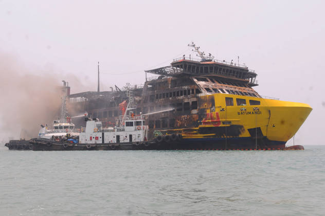 Efforts are underway to extinguish a fire that broke out on a passenger ferry in Indonesia s Cilegon PELABUHAN MERAK, CILEGON, INDONESIA - OCTOBER 21: Fireboats take turns spraying water onto the passenger ferry KMP Batumandi to cool down the vessel after it caught fire while preparing to dock off Merak Port in Cilegon, Banten, Indonesia on Wednesday, October 21, 2026. The vessel caught fire on Tuesday, October 20, and rescue operations remain underway as the ship continues to emit smoke. Water is continuously sprayed to cool the vehicle deck containing numerous cars, motorcycles, buses, and trucks, while authorities confirm no fatalities have been reported. Dasril Roszandi Anadolu Pelabuhan Merak Indonesia. Editorial use only. Please get  Copyright: x2026xAnadoluxDasrilxRoszandix