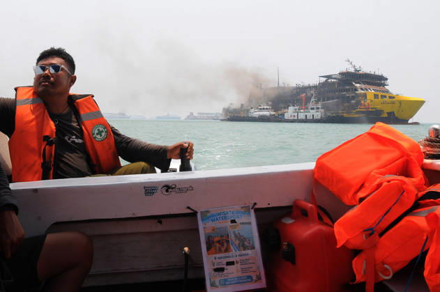 Efforts are underway to extinguish a fire that broke out on a passenger ferry in Indonesia s Cilegon PELABUHAN MERAK, CILEGON, INDONESIA - OCTOBER 21: Fireboats take turns spraying water onto the passenger ferry KMP Batumandi to cool down the vessel after it caught fire while preparing to dock off Merak Port in Cilegon, Banten, Indonesia on Wednesday, October 21, 2026. The vessel caught fire on Tuesday, October 20, and rescue operations remain underway as the ship continues to emit smoke. Water is continuously sprayed to cool the vehicle deck containing numerous cars, motorcycles, buses, and trucks, while authorities confirm no fatalities have been reported. Dasril Roszandi Anadolu Pelabuhan Merak Indonesia. Editorial use only. Please get  Copyright: x2026xAnadoluxDasrilxRoszandix